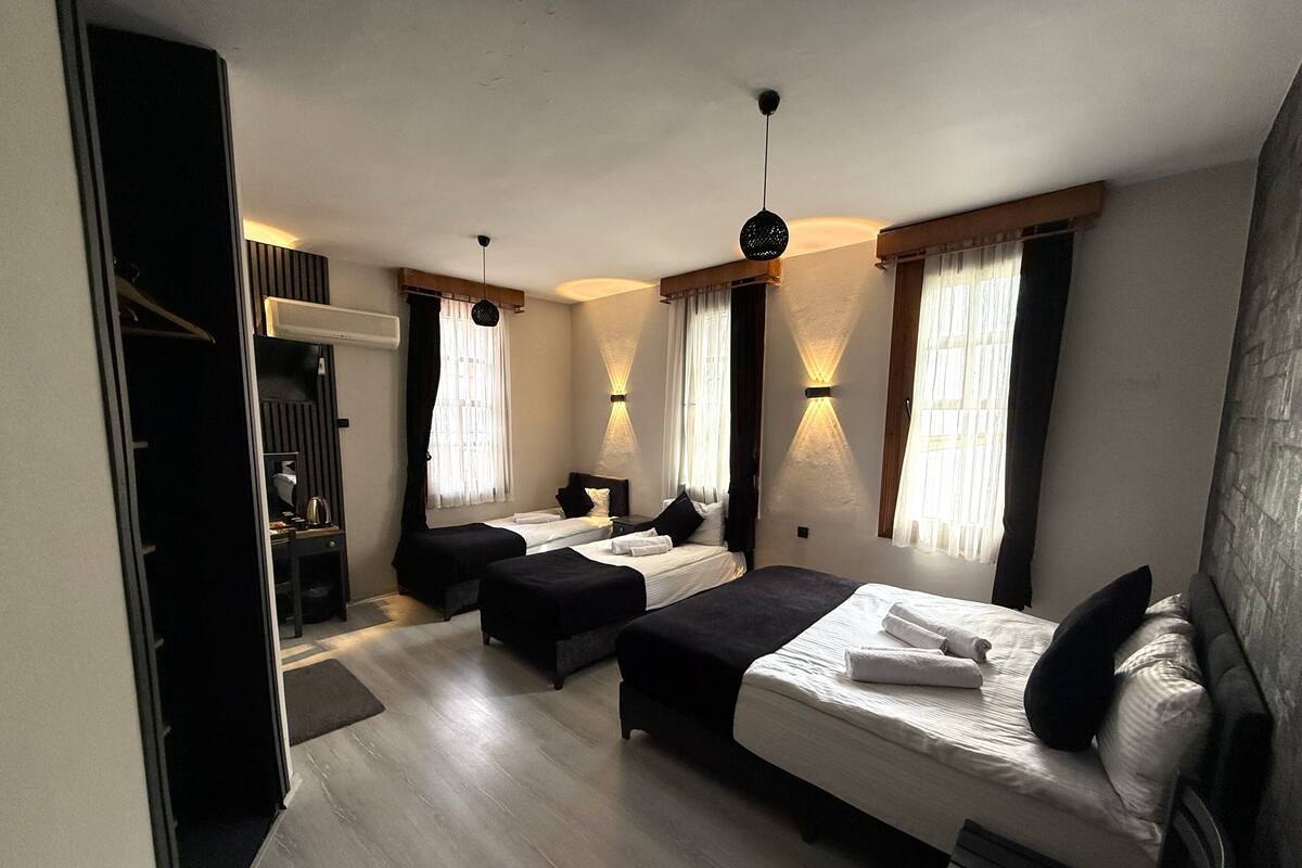 Habitación de hotel con dos camas individuales, un escritorio, una silla, un armario y una lámpara en el techo.