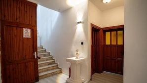 A staircase leading to a room with a white wall and a wooden door with a sign. - bütünoğlu pansiyon (Antalya)