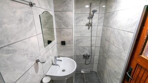 A bathroom with a sink, mirror, and shower. - bütünoğlu pansiyon (Antalya)