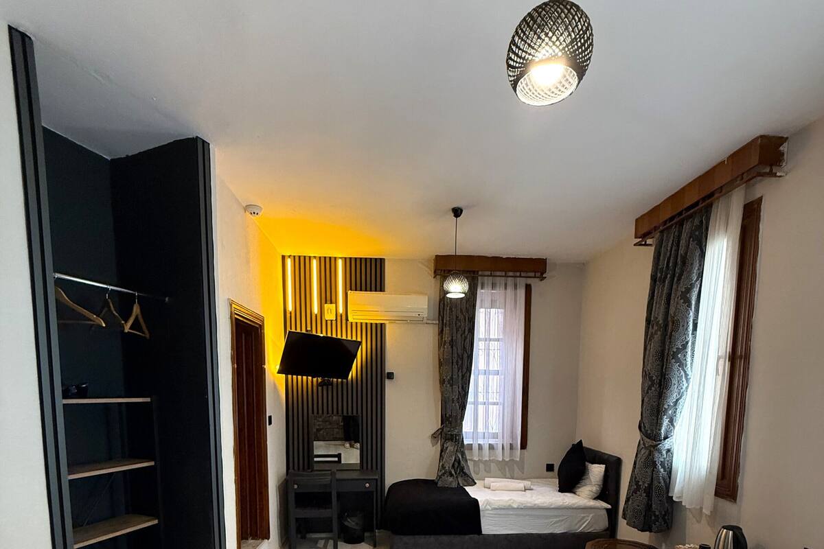 Una habitación de hotel con una cama, un escritorio, un armario y un televisor.
