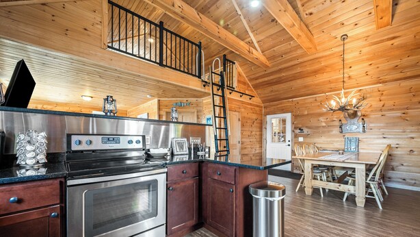 Una cocina con electrodomésticos de acero inoxidable, un comedor de madera y una escalera.