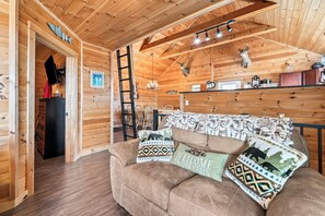 Ein Holzblockhaus-Interieur mit einer Couch, Kissen, einer Chandelier und montierten Tierköpfen.