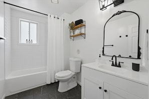 A modern bathroom with a bathtub, toilet, and vanity.