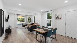 Ein modernes Interieur mit Essbereich, Sofa und großen Fenstern.