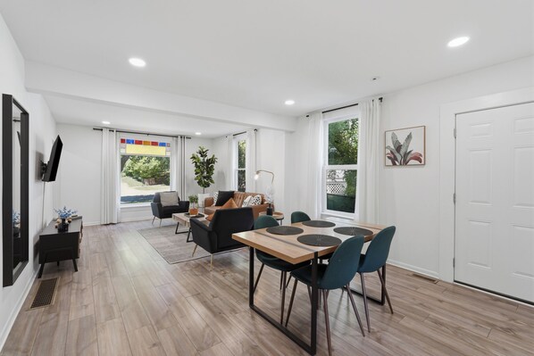 A modern interior with a dining area, sofa, and large windows.