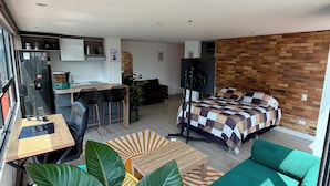 Un interior moderno con cocina, comedor y un dormitorio con pared de ladrillo.