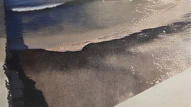 Un hôtel situé sur la côte, doté de nombreux balcons, donnant sur une plage de sable fin et offrant une vue sur un ciel bleu azur.
