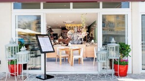 Un restaurant appelé « Bothaï », avec une enseigne au-dessus de l’entrée, un présentoir à menus et des plantes en pot à l’extérieur.