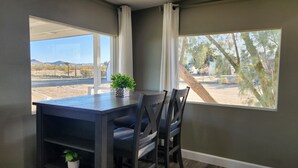 Un espace repas comprenant une table, des chaises et offrant une vue sur un paysage désertique.