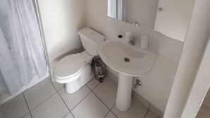 A small bathroom with a toilet, sink, and a trash bin.