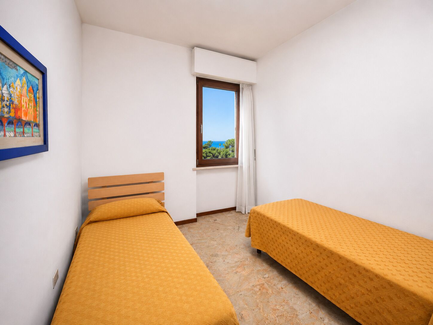 Une chambre avec deux lits, une fenêtre donnant sur un beau paysage et un tableau accroché au mur.