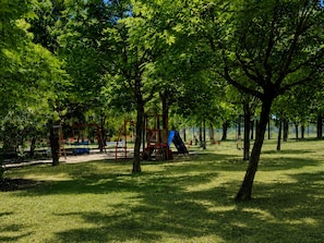 Un parco con attrezzature da gioco, alberi e una zona erbosa.