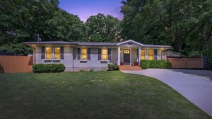 A two-story house with a front porch, a driveway, and a well-maintained lawn. - Modern East ATL Holiday Getaway (Atlanta)
