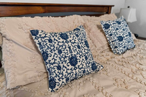 A bed with two decorative pillows and a textured blanket.