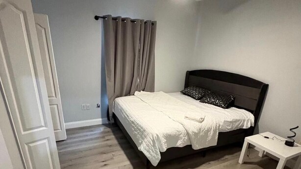 Un dormitorio con cama, ventilador de techo, mesita de noche y una puerta.