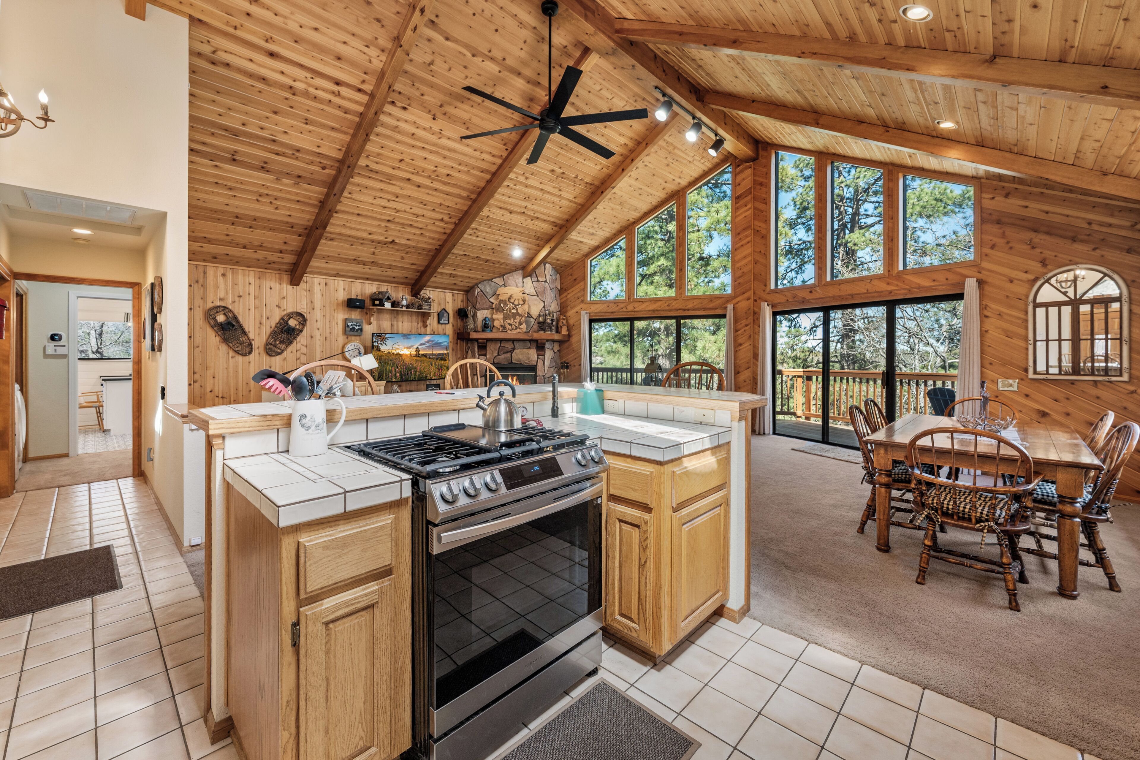 A spacious kitchen with wooden cabinets, a large island, a stove, and a dining area with a table and chairs.