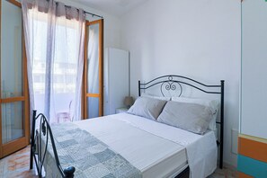 Una camera da letto con un letto, tende, un comodino e una finestra.