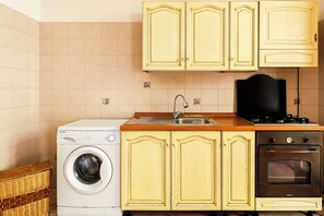 Una cocina compacta con lavadora, un lavamanos, estufa y armarios amarillos.
