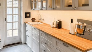 A kitchen with a wooden countertop, white cabinets, a coffee machine, and a kettle. - Amazing home in Hals with sauna (Hals)