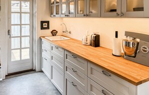 A kitchen with a wooden countertop, white cabinets, a coffee machine, and a kettle. - Amazing home in Hals with sauna (Hals)