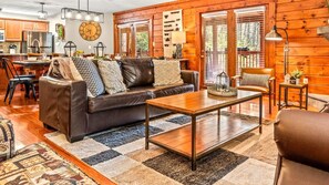 Ein gemütliches Wohnzimmer mit Ledersofa, Couchtisch und Essbereich, inklusive einer Uhr und Holzwänden.