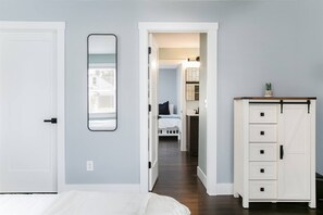 Une chambre à coucher avec un lit, une commode et un miroir au mur.
