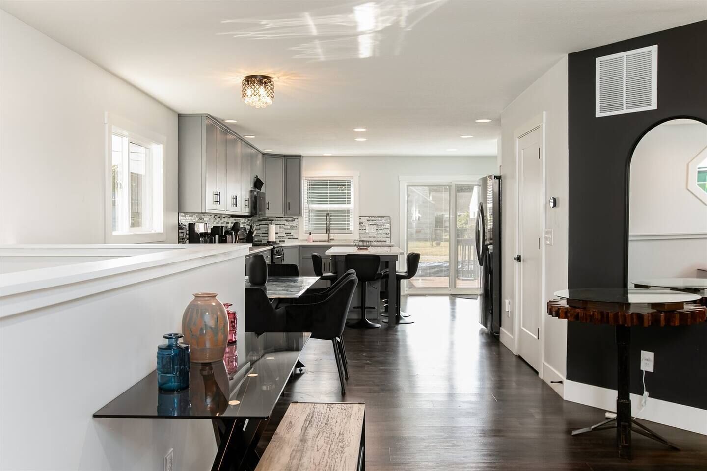 A modern kitchen with a dining area, large windows, and a sliding glass door leading to a patio.