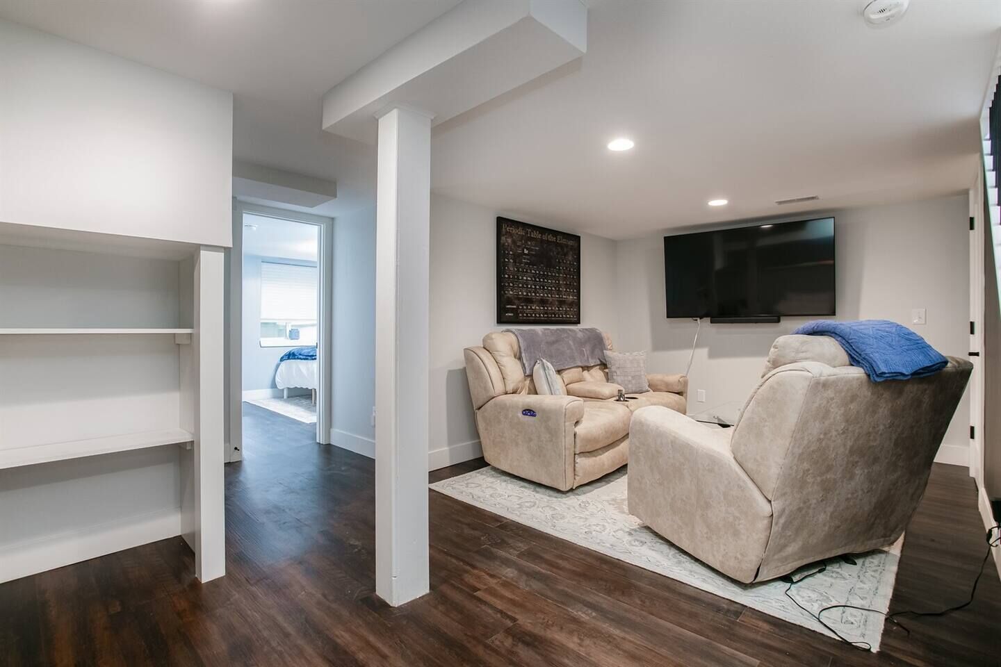 A modern living room with a sectional sofa, a flat-screen TV, and a wall-mounted artwork.