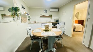 Une cuisine compacte avec un coin repas, une horloge et un lit dans la pièce adjacente.