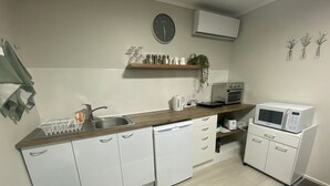 Une cuisine moderne avec des meubles blancs, un four à micro-ondes, une machine à café et une horloge murale.