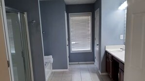 Et badeværelse med toilet, håndvask og et vindue med skodder.