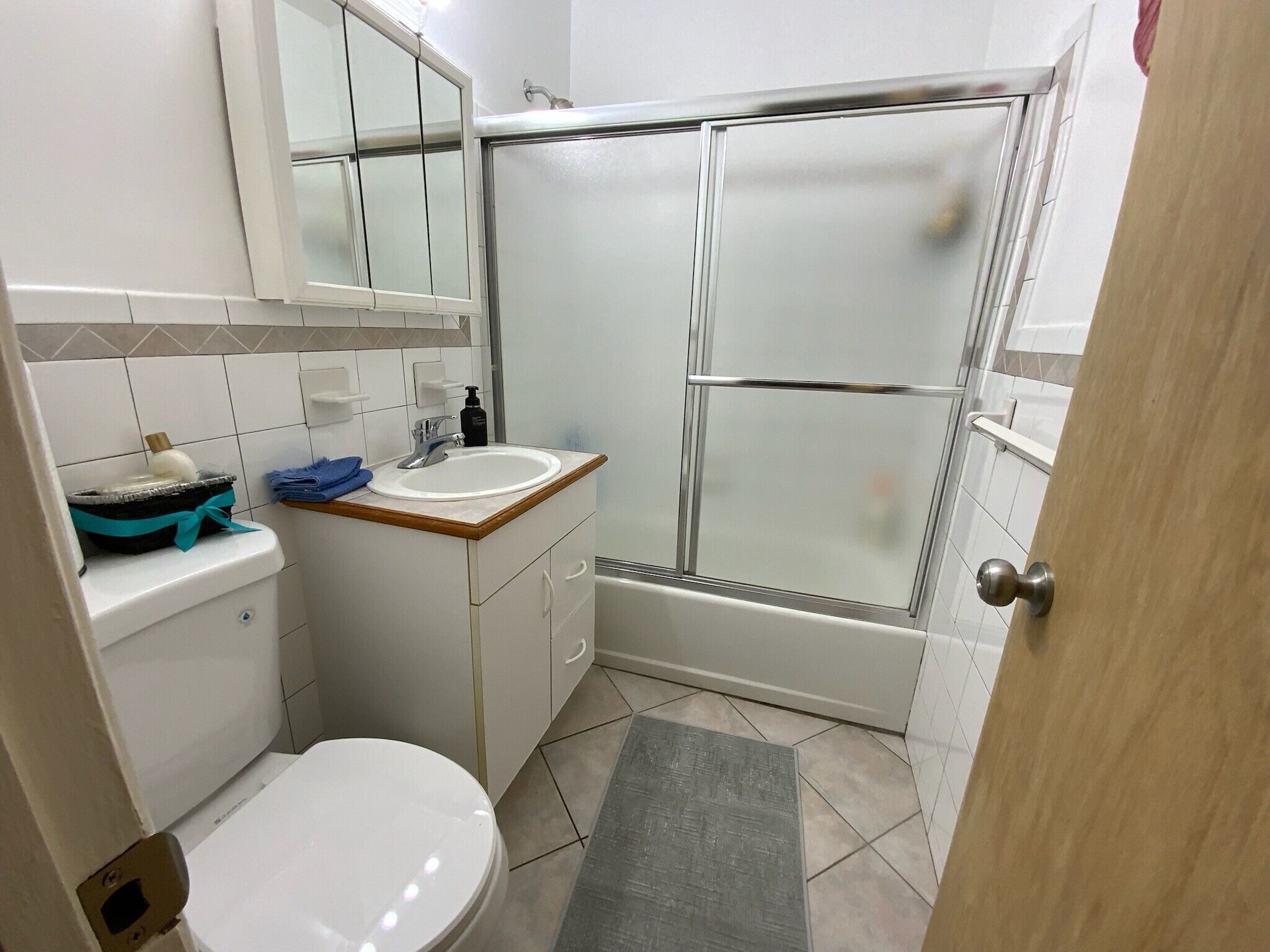 A bathroom with a toilet, sink, mirror, and glass shower enclosure.
