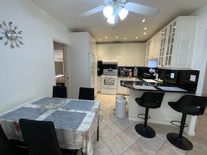 A modern kitchen with white cabinets, a black countertop, and a ceiling fan.