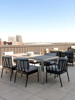 A rooftop patio with a dining table and chairs, a sofa, and a view of the city skyline. - The Edison Old City | Premier 2 BR Suite w/ Shared Roofdeck (Philadelphia)