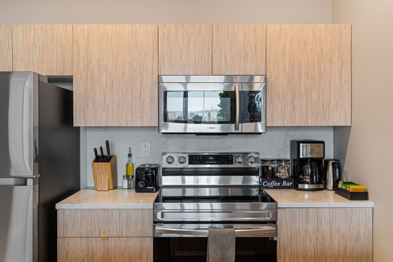 A modern kitchen with stainless steel appliances, wooden cabinets, a coffee bar, and a knife block.