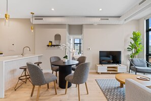 A modern living space with a kitchen, dining area, and seating area. - The Edison Old City | Premier 2 BR Suite w/ Shared Roofdeck (Philadelphia)