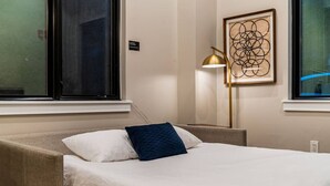 Una camera d'albergo con un letto, una lampada e un'opera d'arte astratta incorniciata al muro.