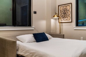 A hotel room with a bed, a lamp, and a framed abstract artwork on the wall. - The Edison Old City | Accessible 1 BR Suite w/ Shared Roofdeck | Ground Floor (Philadelphia)