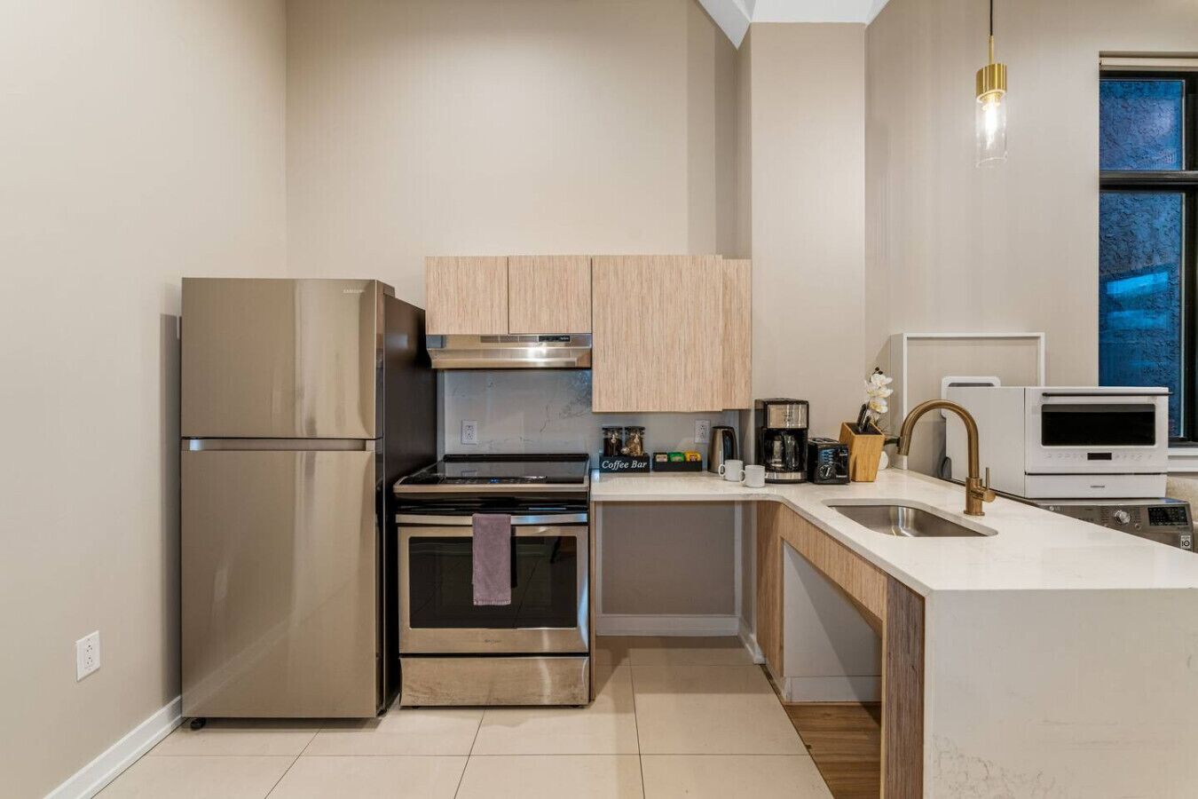 Una cocina moderna con electrodomésticos de acero inoxidable, horno empotrado, una zona para café y un ventanal con vistas.
