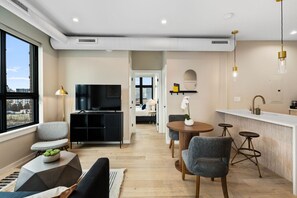 A modern living room with a TV, seating, a dining area, and a kitchen. - The Edison Old City | Signature 2 BR Suite w/ Shared Roofdeck (Philadelphia)