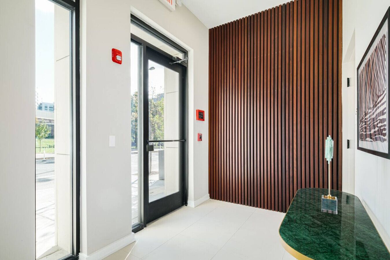 A modern interior with a glass door, a wooden slatted wall, and a marble counter.