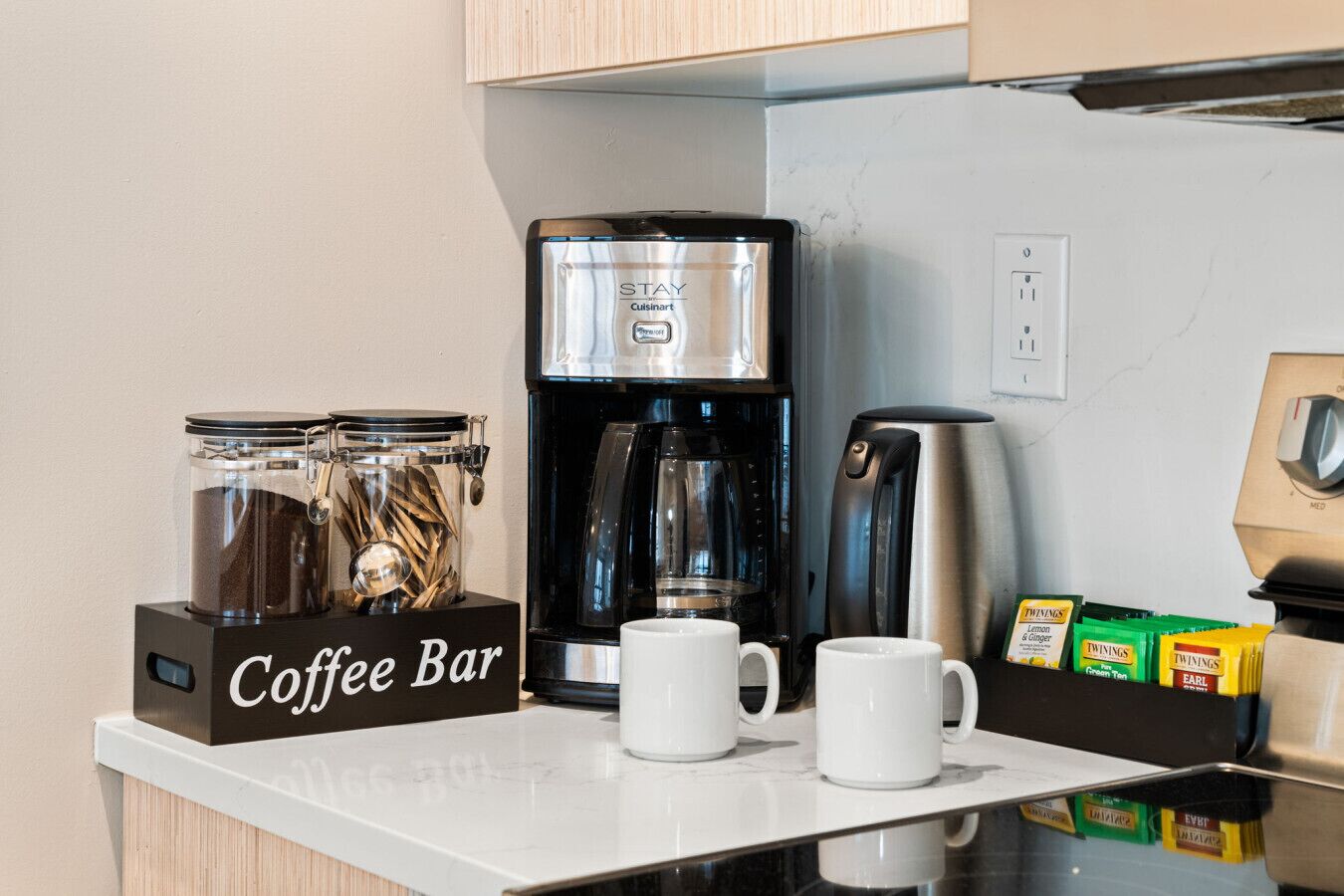 A coffee bar with a coffee maker, a coffee grinder, and a coffee bean container.
