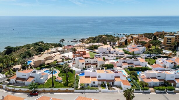 Un quartier résidentiel situé sur la côte, avec des bâtiments blancs, une piscine et une vue sur la mer.