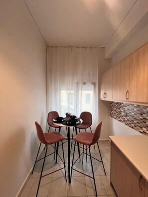 Une cuisine de taille réduite avec une table à manger, quatre chaises et un pare-feu en carreaux.