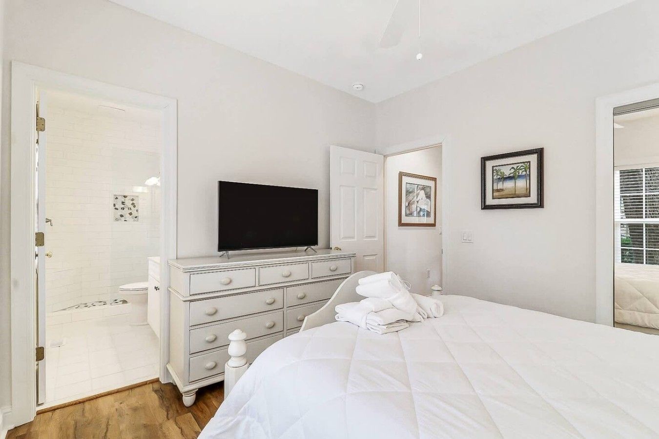 A hotel room with a bed, a dresser, a television, and a shower area.