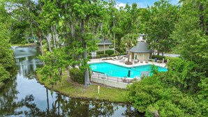 A pool surrounded by lush greenery and trees, with a small gazebo and lounge chairs nearby. - Golf Course Corner Villa First Floor Views (Hilton Head Island)