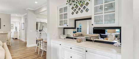 A modern kitchen with white cabinetry, a central island, and a hanging plant.