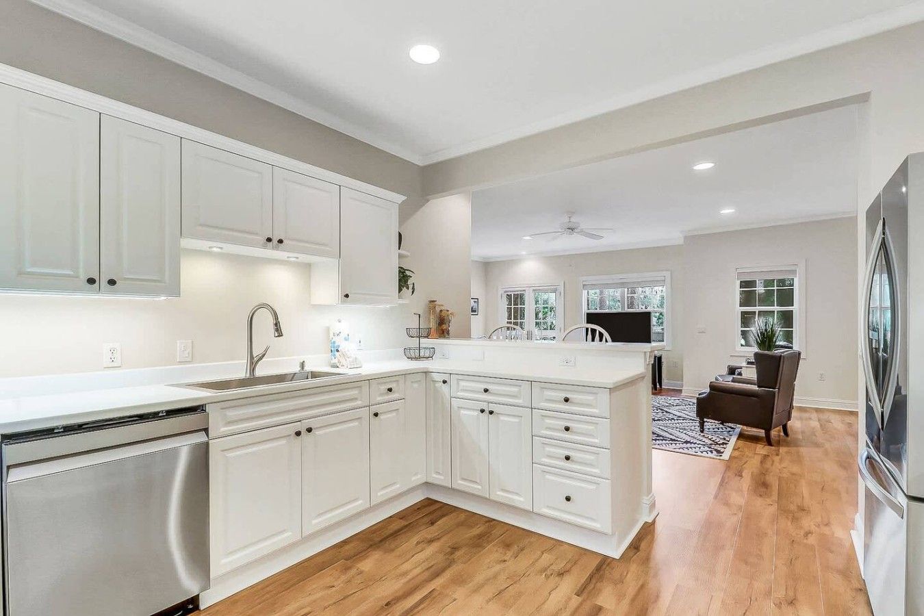 A modern kitchen with white cabinetry, a built-in dishwasher, and a large island with a sink.