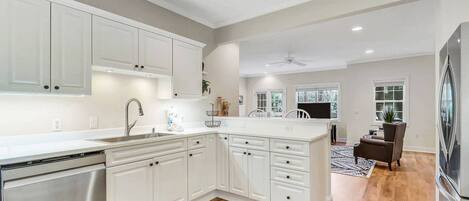 A modern kitchen with white cabinetry, a built-in dishwasher, and a large island with a sink.