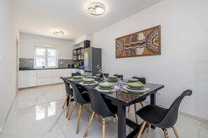 Un comedor moderno con una mesa de vidrio, sillas negras y un adorno en la pared.